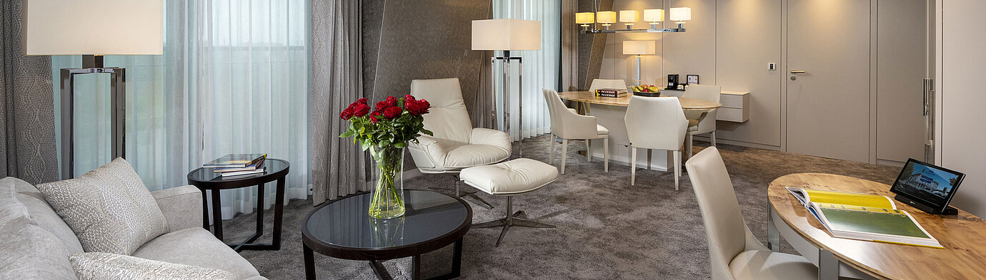 Hochwertig ausgestattete Suite mit stilvollem Interieur, Sitzbereich, Esstisch und eleganten Dekorationselementen.