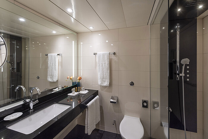 Elegantes Duschbad mit großer Spiegelfläche und schwarzen Akzenten im Maritim Hotel Ulm