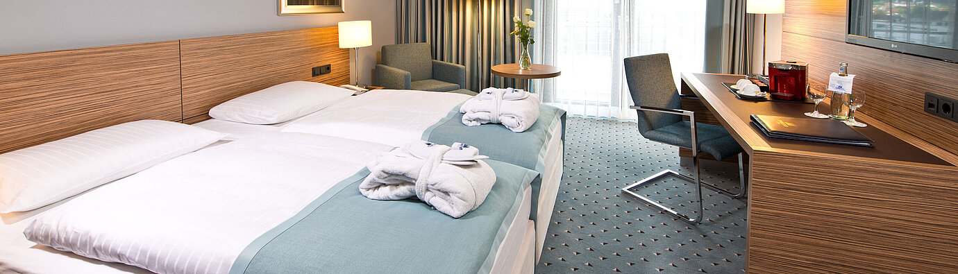 Superior Zimmer im Maritim Darmstadt mit stilvollem Design, Schreibtisch, gemütlicher Sitzecke und Doppelbett mit Bademänteln