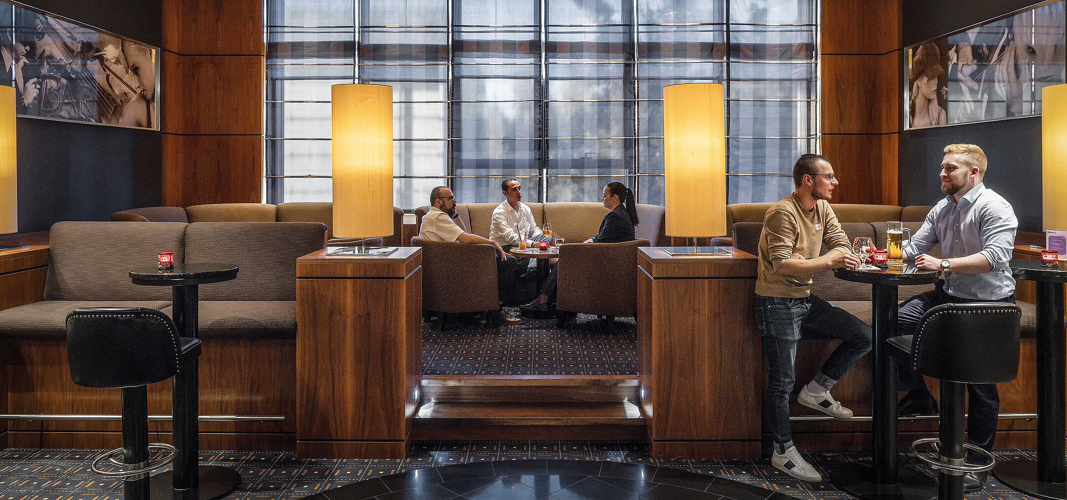 Gemütliche Sitzbereiche in der Hotelbar des Maritim Hotel Düsseldorf mit moderner Beleuchtung und Gästen im Gespräch.