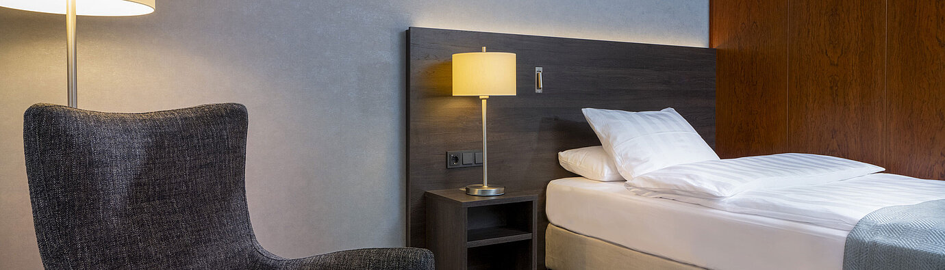 Superior Queen Zimmer Modernes Superior Queen Zimmer im Maritim Hotel Bremen mit gemütlichem Sessel, Nachttisch und stimmungsvoller Beleuchtung.