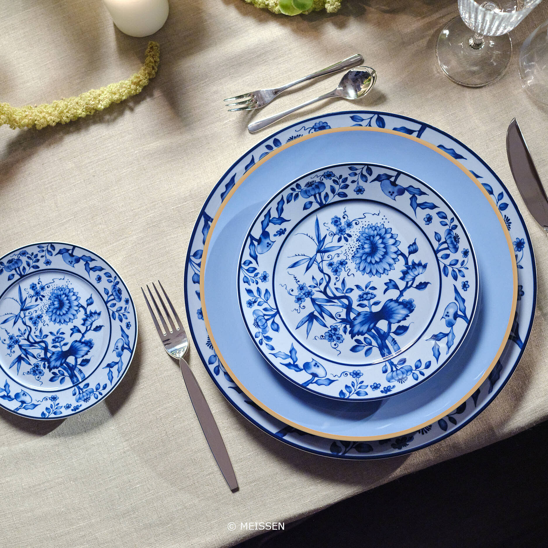 Edles blaues Meissener Porzellan mit Blumenmuster auf festlich gedecktem Tisch mit Besteck und Gläsern