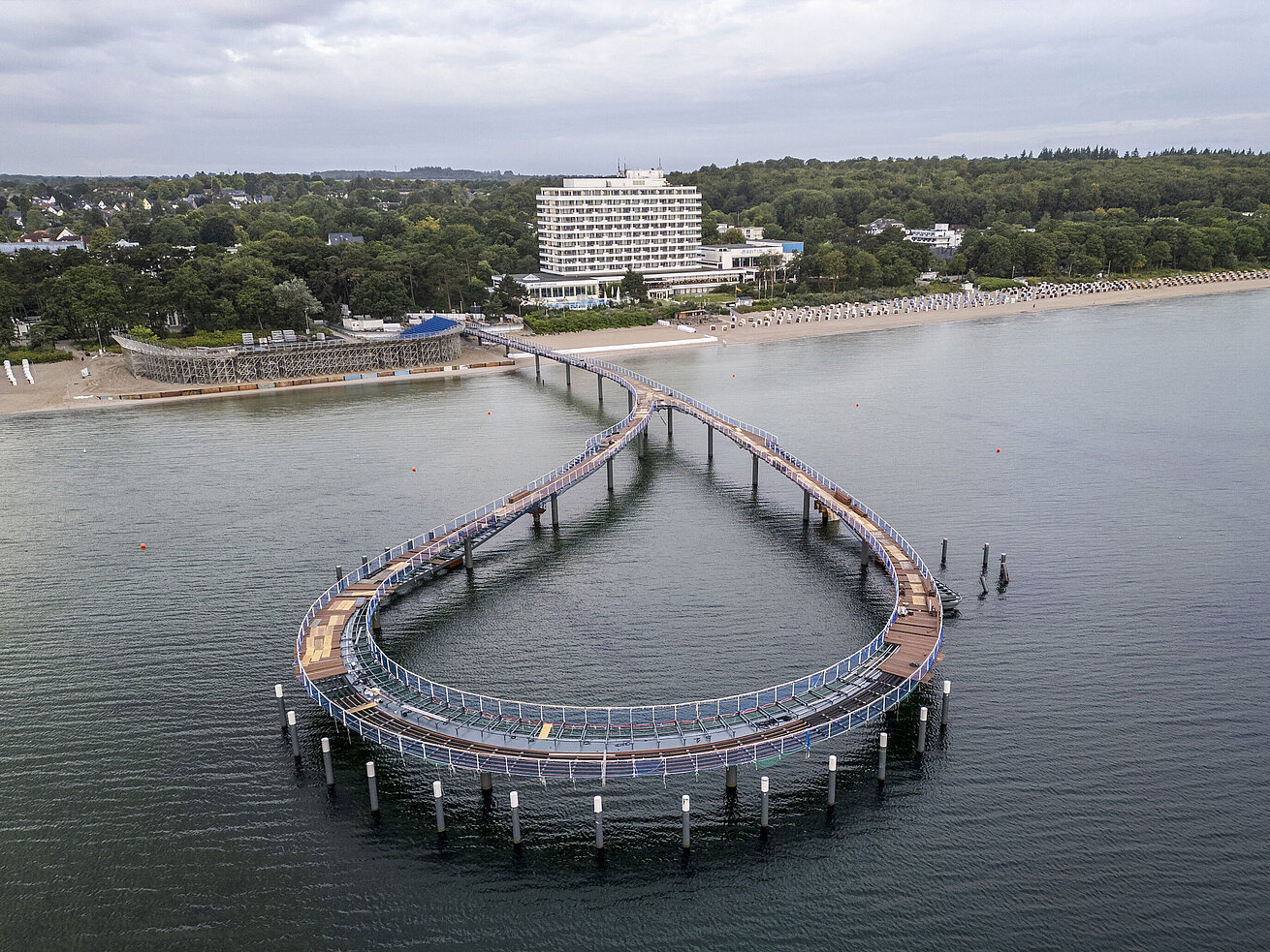 Seebrücke vor dem Maritim Seehotel Timmendorfer Strand mit ruhigem Wasser und blauem Himmel.