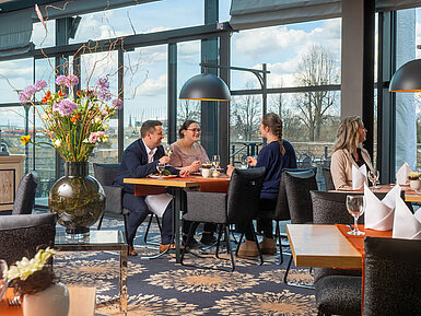 Restaurant Wintergarten Gäste genießen Speisen im Restaurant des Maritim Hotel Dresden mit Blick nach draußen.