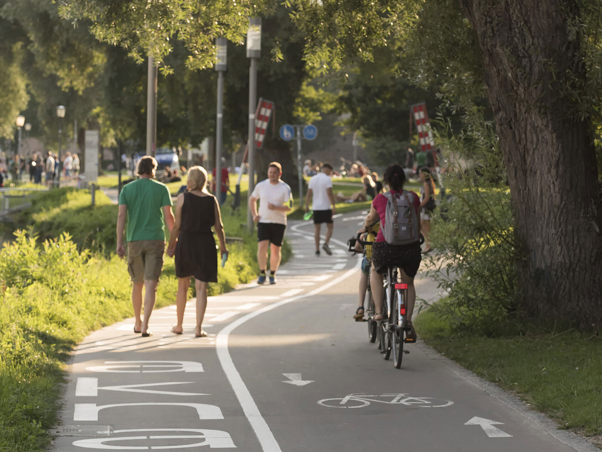 Donaupromenade Ulm – Stadtimpression Fußgänger und Radfahrer an der Donaupromenade in Ulm bei Sonnenschein.
