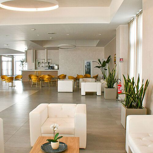 Lichtdurchflutete Lobby des Maritim Resort Calabria mit weißen Sesseln und gelben Stühlen
