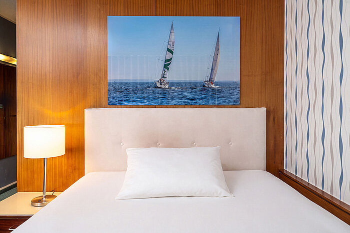 Classic Queen Zimmer Queensize-Bett im Classic Queen Zimmer mit Nachttischlampe und maritimem Wandbild