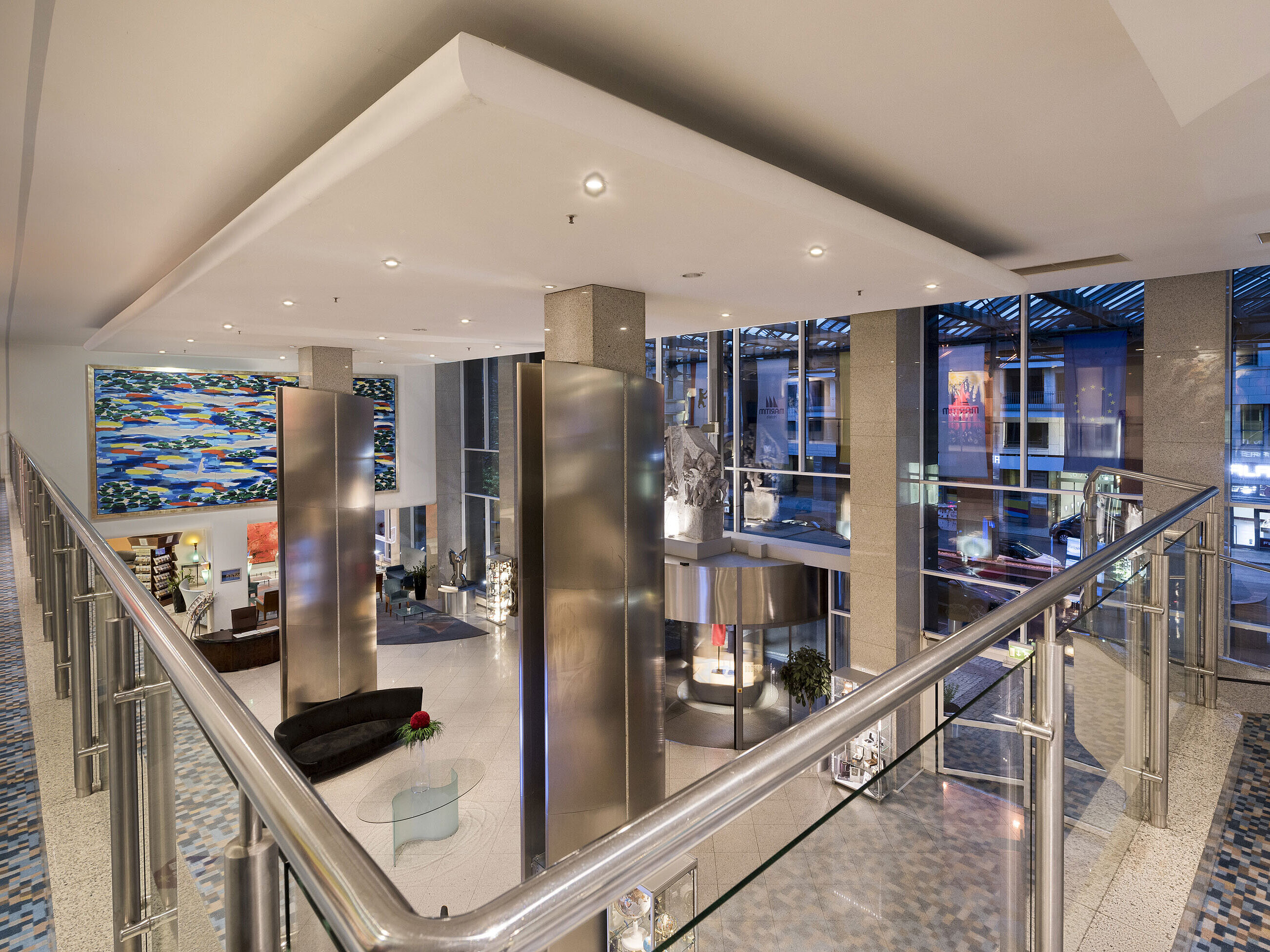 Blick von oben auf die moderne Lobby des Maritim proArte Hotels Berlin mit großem Kunstwerk und Glaswänden.