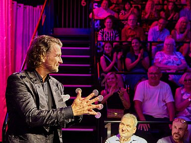 STROTMANNS Magic Lounge Entertainer bei einer Live-Show vor Publikum in stimmungsvoll beleuchtetem Veranstaltungsraum.