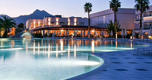Poolbeleuchtung am Abend im Maritim Resort Calabria mit Palmen und Gebirgskulisse
