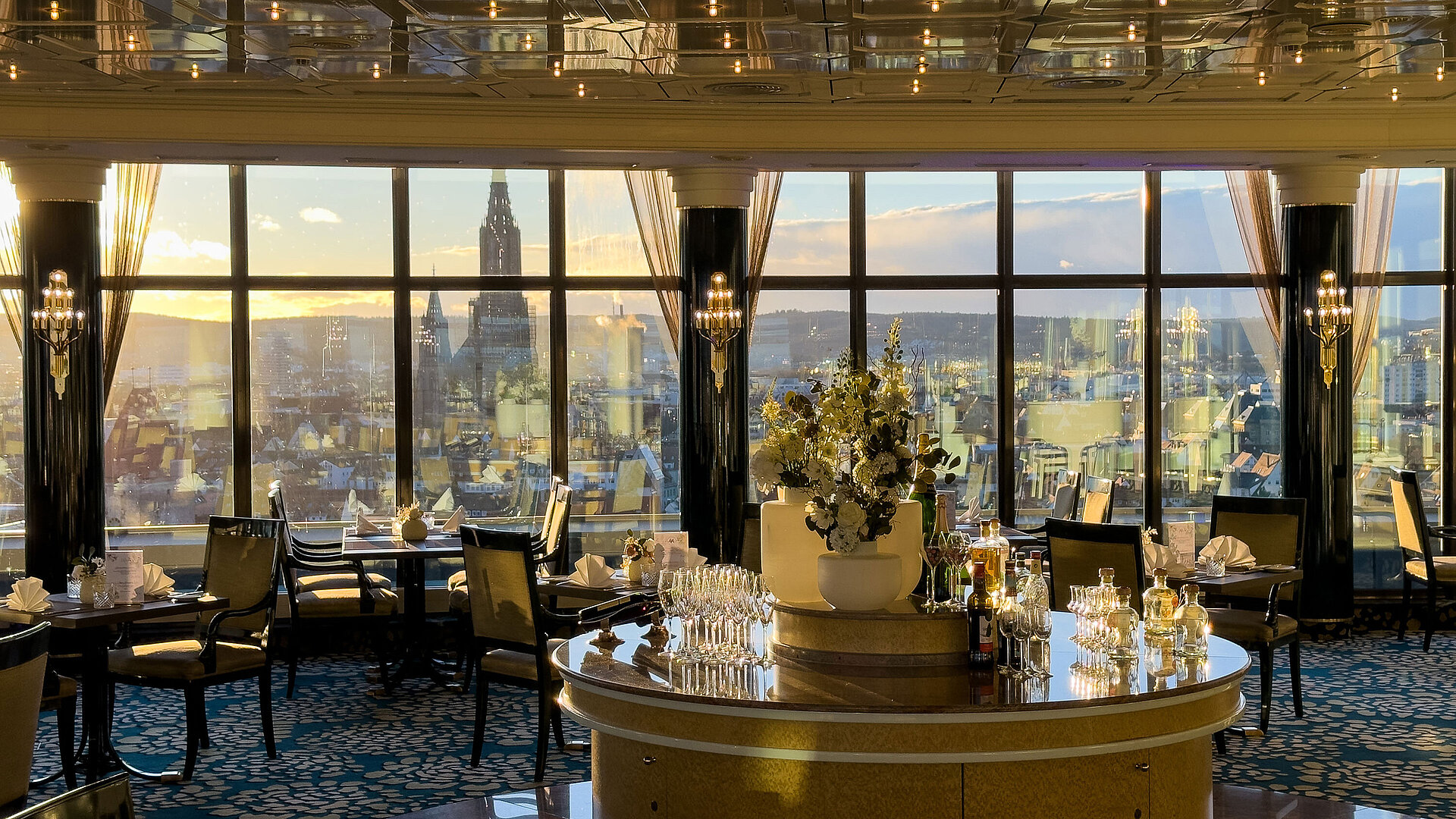 Elegantes Restaurant im Maritim Hotel Ulm mit großen Panoramafenstern und Blick über die Stadt bei Sonnenuntergang