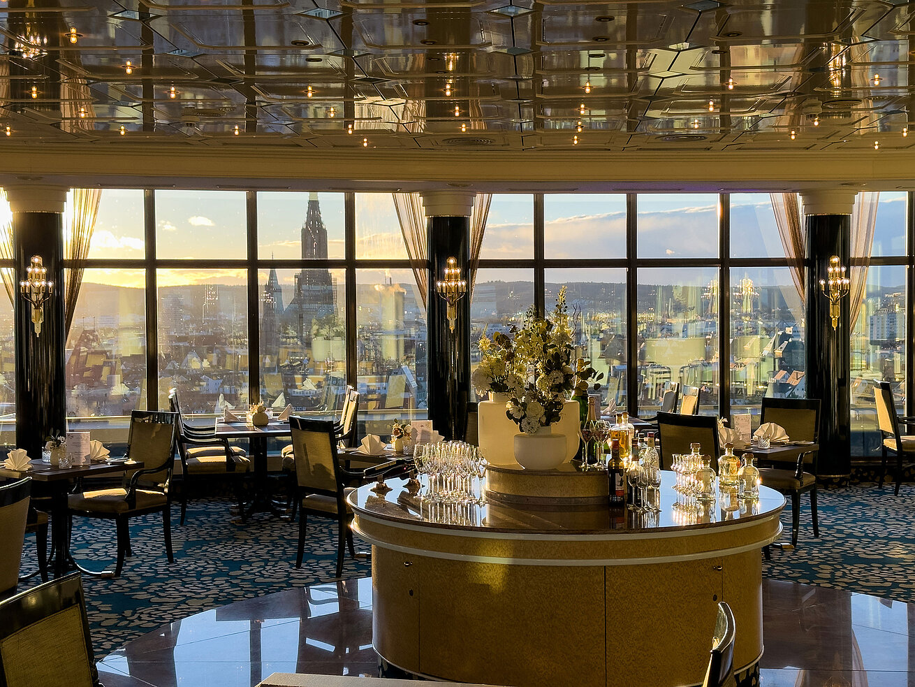 Elegantes Restaurant im Maritim Hotel Ulm mit großen Panoramafenstern und Blick über die Stadt bei Sonnenuntergang