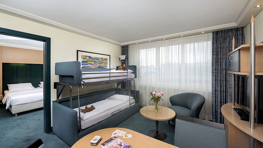 Familiensuite mit Etagenbett, Sofa, Tisch und Blick ins Schlafzimmer im Maritim proArte Hotel Berlin
