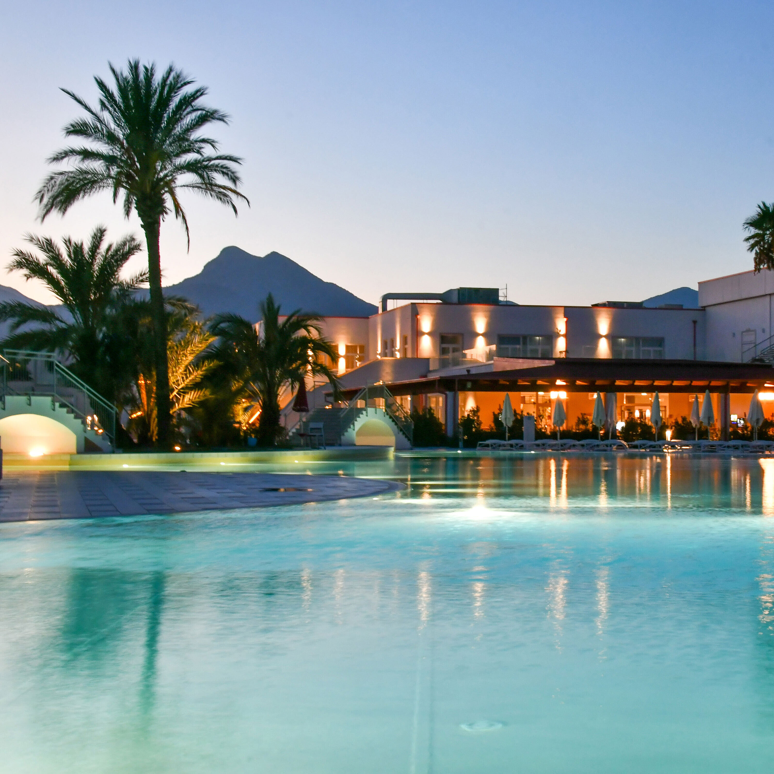 Poolbeleuchtung am Abend im Maritim Resort Calabria mit Palmen und Gebirgskulisse