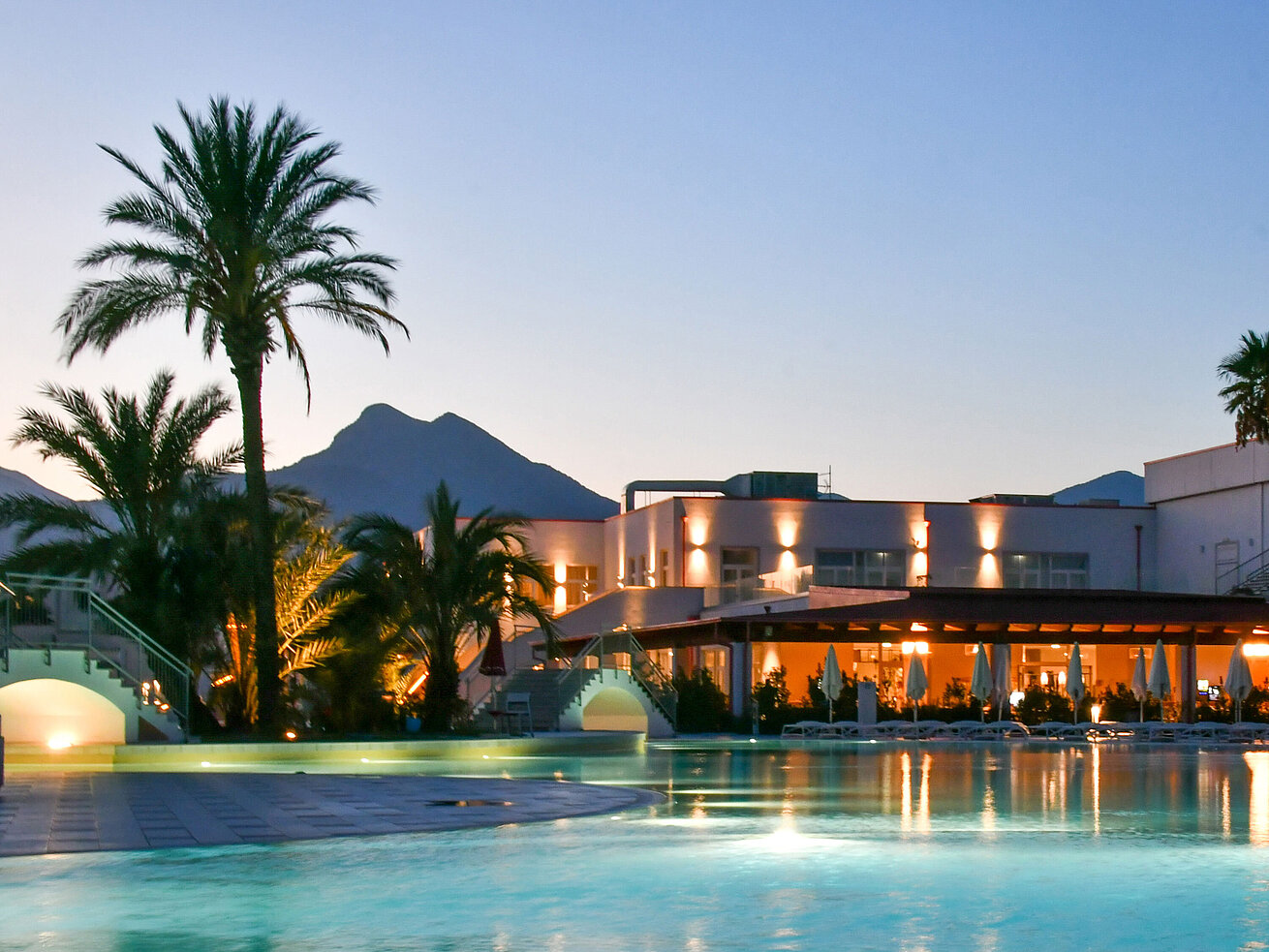Poolbeleuchtung am Abend im Maritim Resort Calabria mit Palmen und Gebirgskulisse