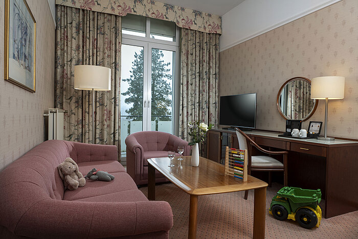 Familienfreundliche Sitzecke mit Spielzeug, Sofa, TV und Balkon im Maritim Hotel Bad Wildungen