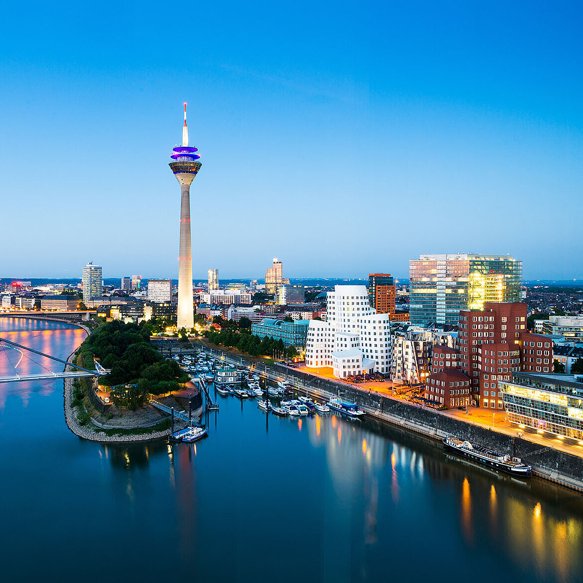 Düsseldorf Skyline mit Rheinturm, Rheinpromenade und moderner Architektur bei Abenddämmerung.