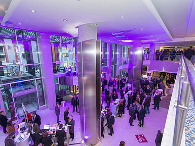 Lobby in Berlin Eine Abendveranstaltung im Maritim Hotel Berlin. Die Lobby ist in lila Licht getaucht, und viele Gäste unterhalten sich.