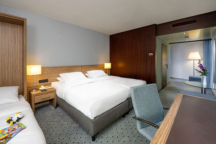 Blick in das Comfort Familienzimmer des Maritim Hotel Darmstadt mit drei Betten und separatem Wohnbereich