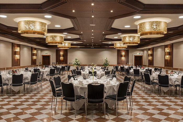 Eleganter Festsaal im Maritim Hotel Königswinter mit runden Tischen, stilvoller Dekoration und Kronleuchtern.