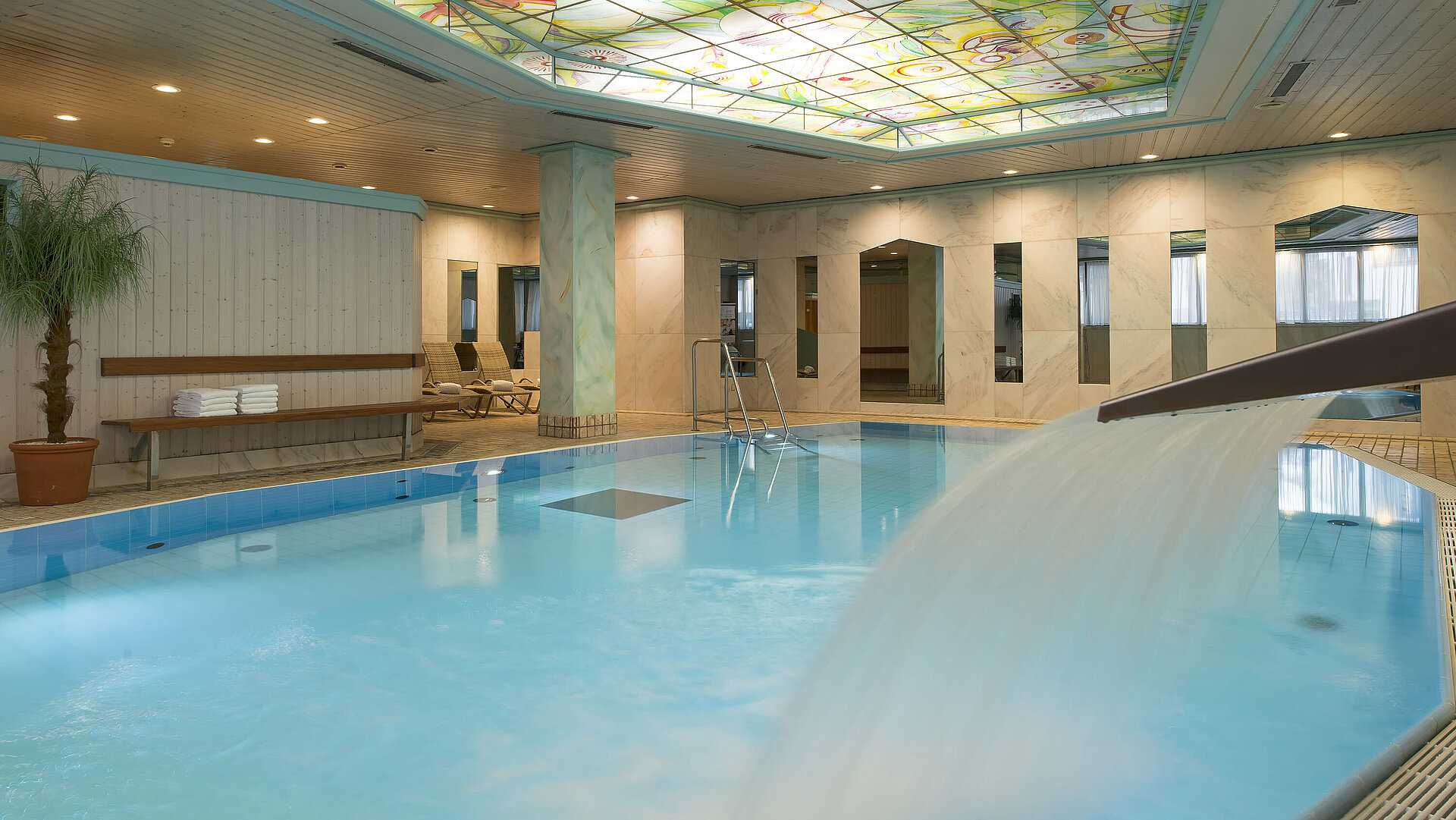Beheizter Innenpool mit Wasserfall und bunter Glasdecke im Maritim Hotel Stuttgart
