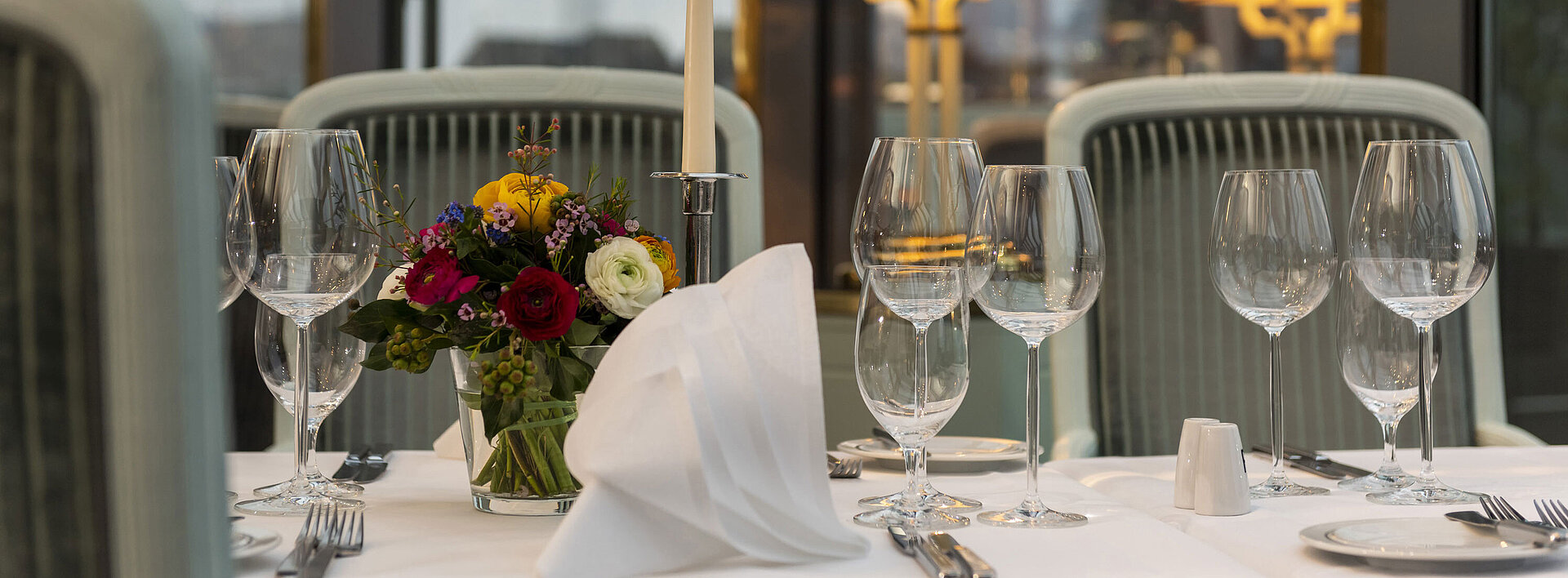 Restaurant "Bellevue" Elegant gedeckter Tisch im Restaurant mit Kerze, Weingläsern und Blumenarrangement, perfekt für ein gehobenes Abendessen.