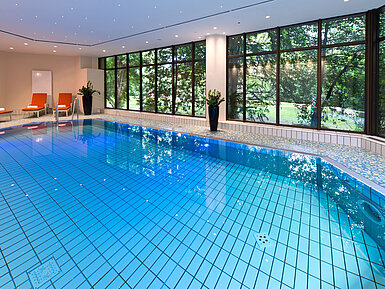 Moderner Innenpool im Maritim Hotel Bad Homburg mit stilvoller Wellenwand und bequemen Liegen.