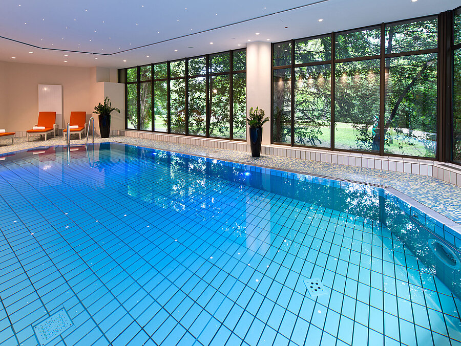 Moderner Innenpool im Maritim Hotel Bad Homburg mit stilvoller Wellenwand und bequemen Liegen.