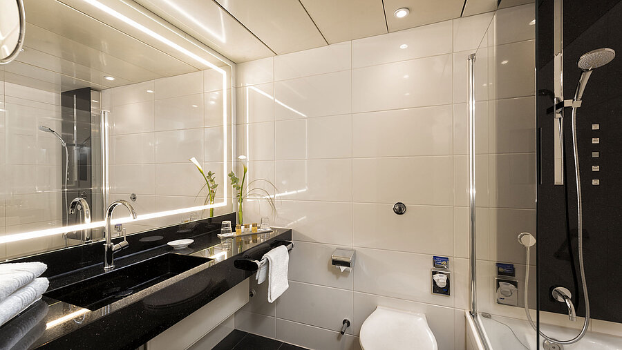 Modernes Badezimmer mit Dusche und Badewanne im Maritim Hotel Bonn, ausgestattet mit eleganten Armaturen und Spiegelbeleuchtung.