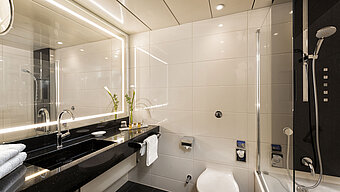 Modernes Badezimmer mit Dusche und Badewanne im Maritim Hotel Bonn, ausgestattet mit eleganten Armaturen und Spiegelbeleuchtung.
