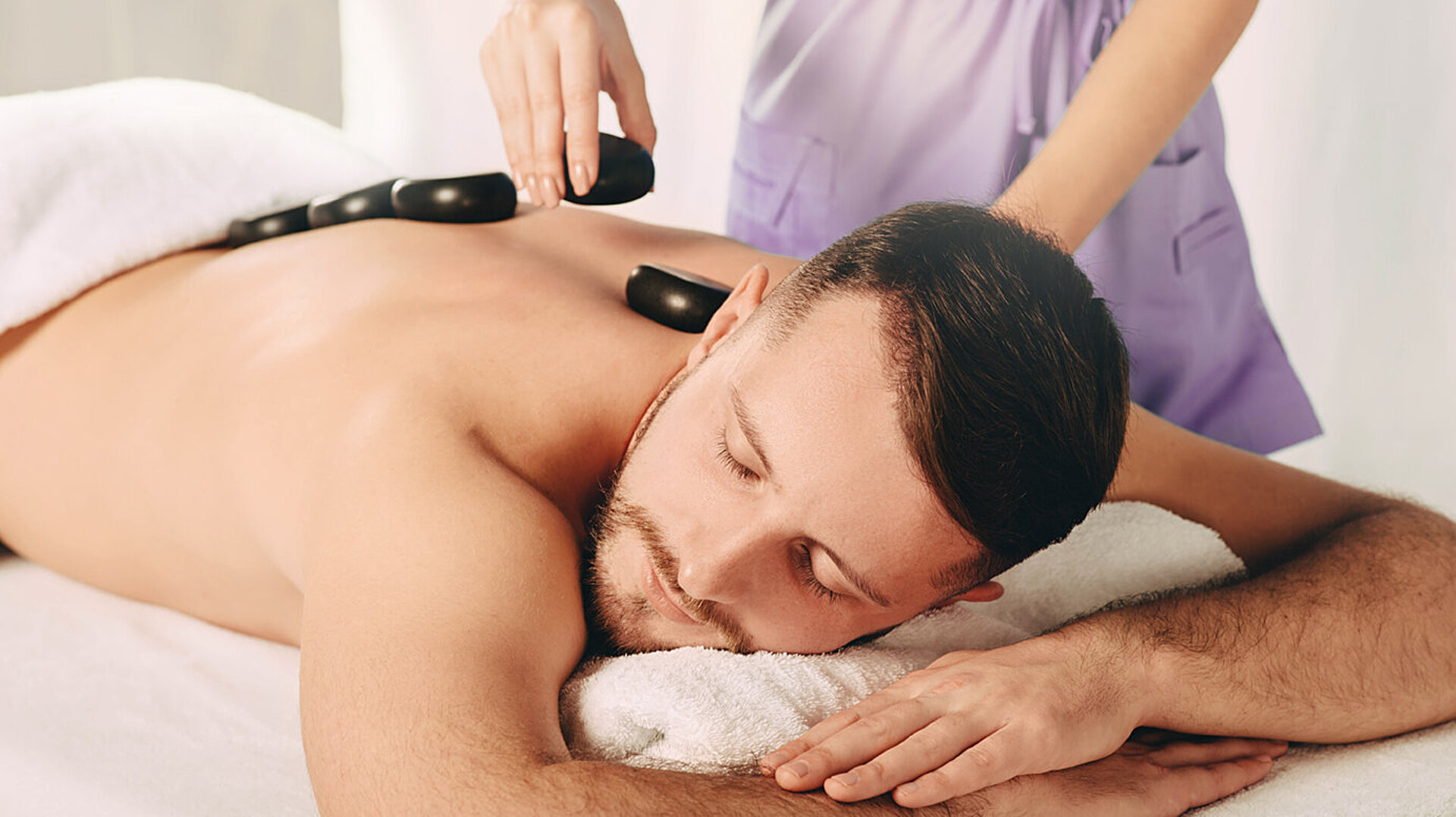 Mann genießt wohltuende Hot-Stone-Massage im Spa für tiefe Entspannung