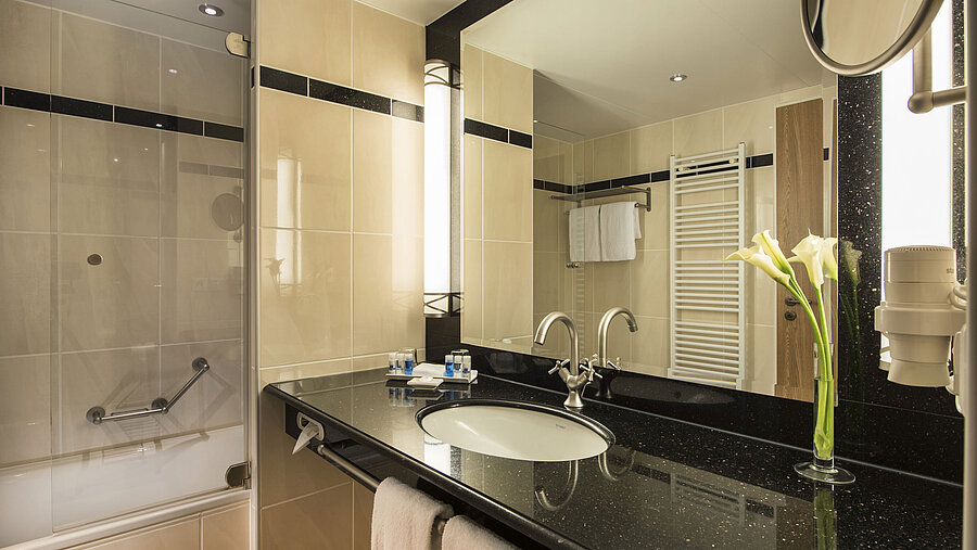 Modernes Badezimmer mit Waschbecken, Spiegel, Badewanne und eleganten Details im Maritim Hotel Dresden.