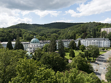 Blick auf das Maritim Hotel Bad Wildungen, umgeben von Bäumen und der grünen Landschaft des Kurparks.