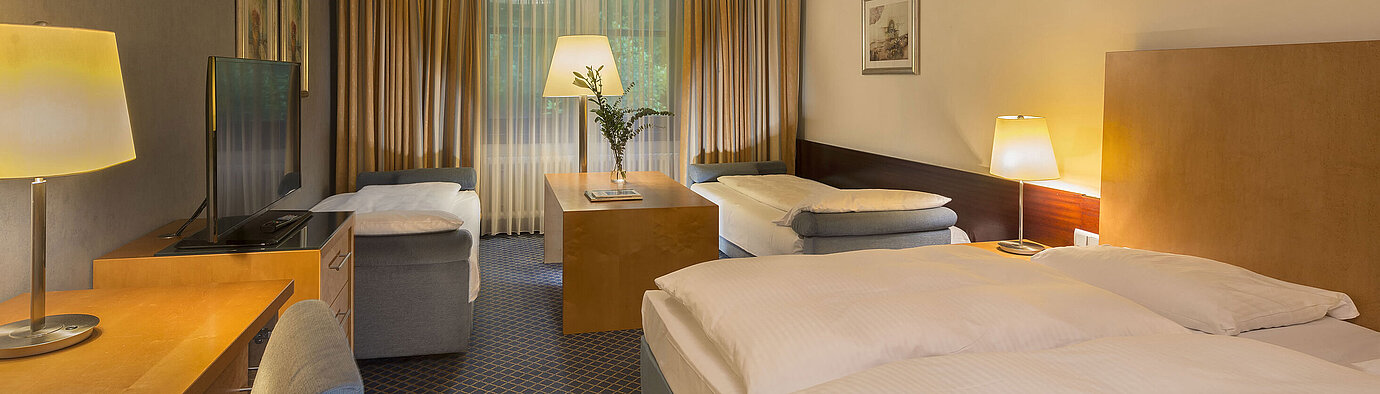 Geräumiges Familienzimmer im Maritim Hotel Fulda mit vier Betten, Schreibtisch und gemütlicher Atmosphäre.