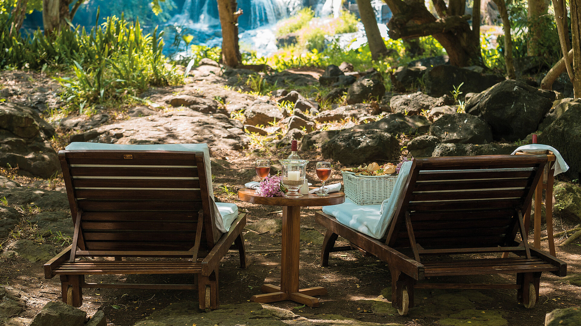 Picknick am Wasserfall Zwei Liegestühle mit Tisch im Grünen vor Wasserfall für entspannte Auszeit