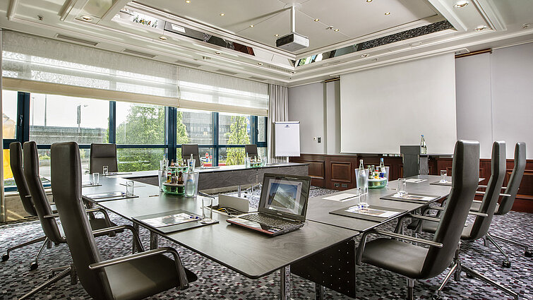 Heller Tagungsraum mit großem Konferenztisch, Ledersesseln und moderner Technik im Maritim Hotel Hannover.