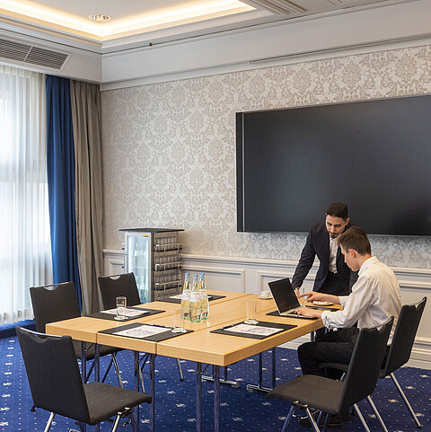Zwei Personen arbeiten im Salon Oegg des Maritim Hotel Würzburg mit modernem Bildschirm.