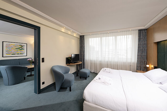 Schlafzimmer der Suite mit Doppelbett und Blick ins Wohnzimmer im Maritim proArte Hotel Berlin