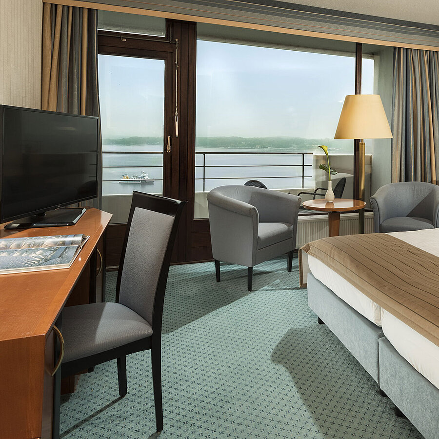 Superior Zimmer im Maritim Hotel Kiel mit Schreibtisch, Sitzbereich, großem Doppelbett und Balkon mit Blick auf die Förde.