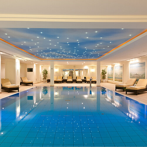 Luxuriöses Hallenbad im Maritim Hotel Dresden mit Liegen und stimmungsvollem Licht an der Decke.