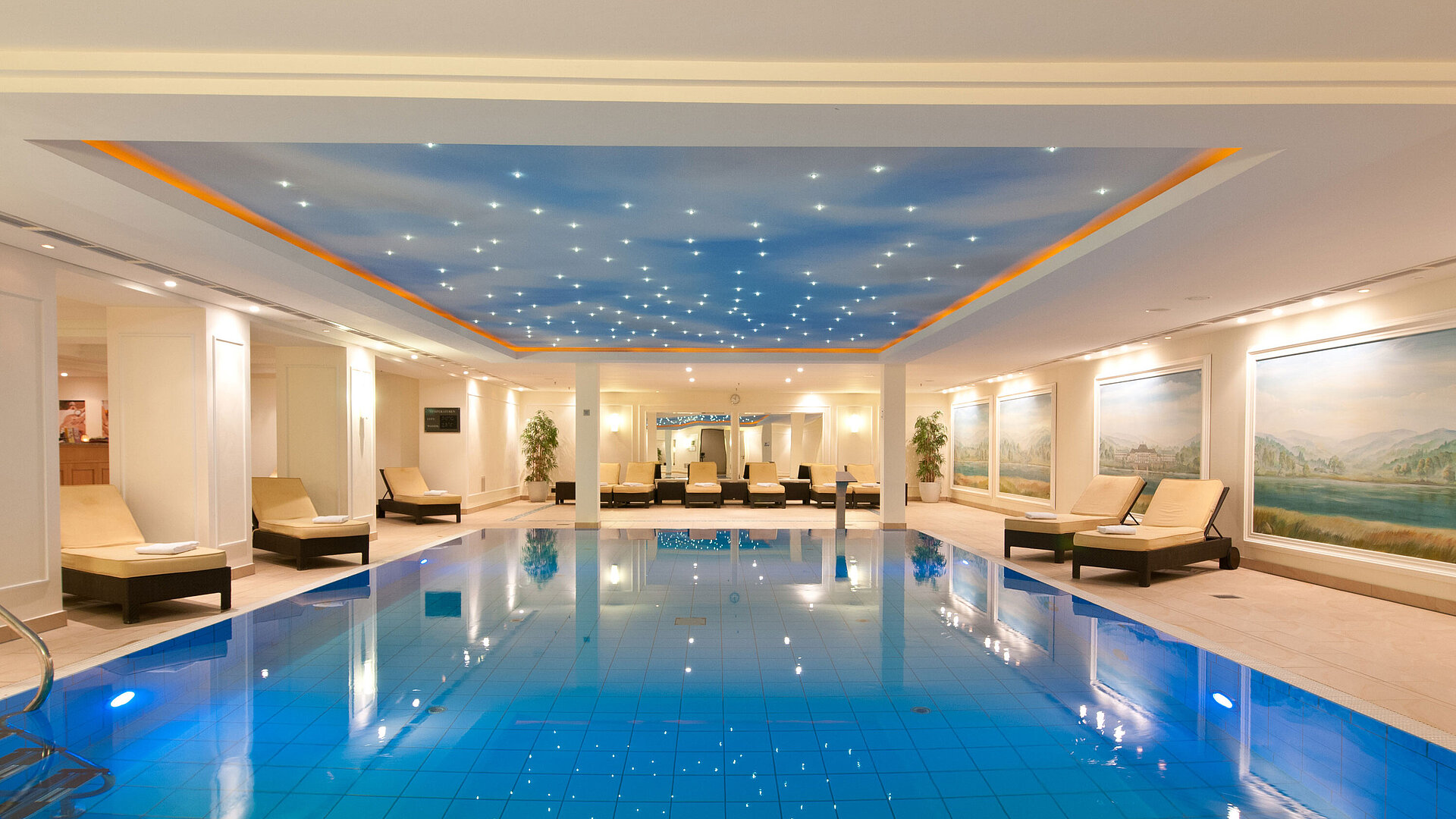Luxuriöses Hallenbad im Maritim Hotel Dresden mit Liegen und stimmungsvollem Licht an der Decke.