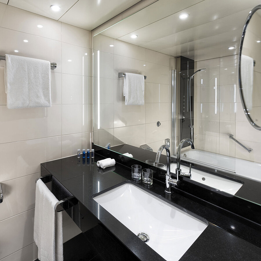 Modernes Badezimmer im Maritim Hotel Ulm mit Wannenbad und stilvoller Beleuchtung.