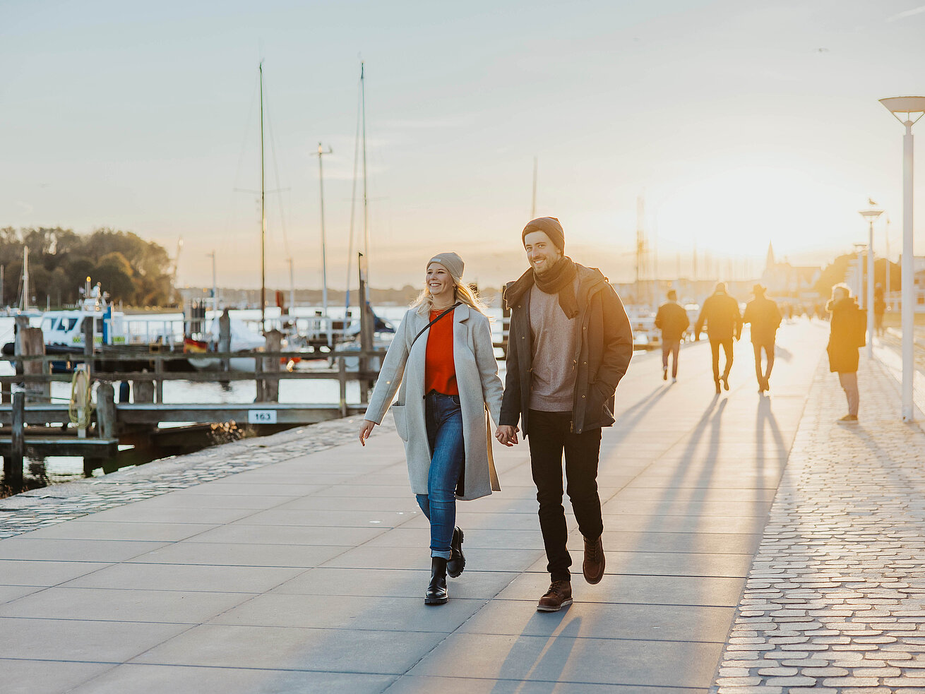 Promenade Travemünde Zwei Personen spazieren an der Strandpromenade in Travemünde bei Sonnenuntergang