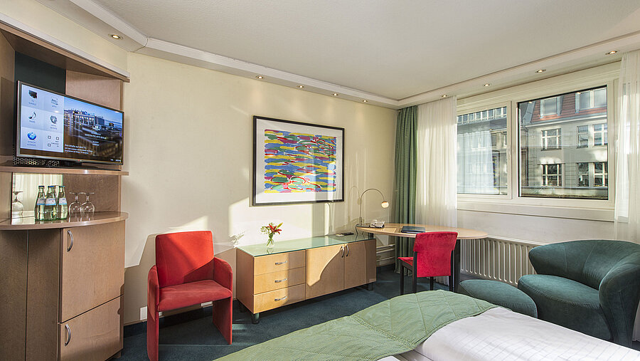 Helles Classic-Zimmer im Maritim proArte Hotel Berlin mit moderner Einrichtung, gemütlicher Sitzgelegenheit und Stadtblick.