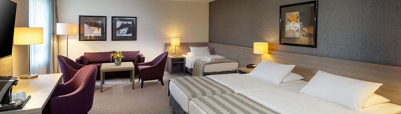 Classic Familienzimmer im Maritim Hotel Königswinter mit Doppelbett, Schlafsofa und gemütlicher Sitzecke.