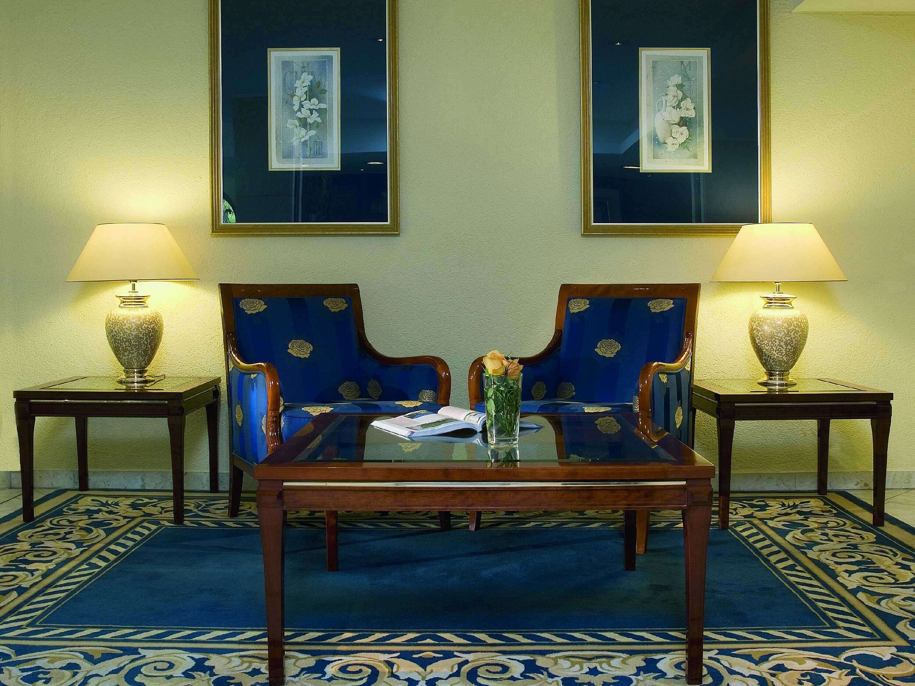  Elegante Lobby im Maritim Hotel Fulda mit blauen Sesseln, Glastisch und stilvoller Beleuchtung.