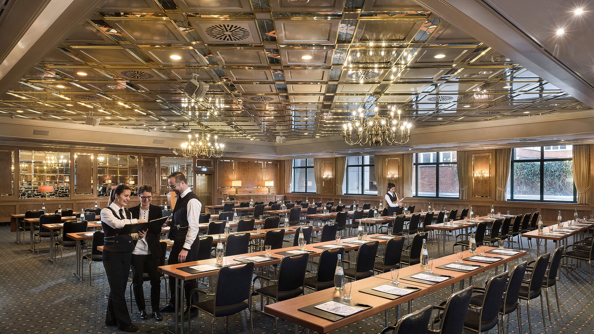 Zwei Mitarbeitende bereiten einen Konferenzraum mit Reihenbestuhlung im Maritim Hotel Stuttgart vor