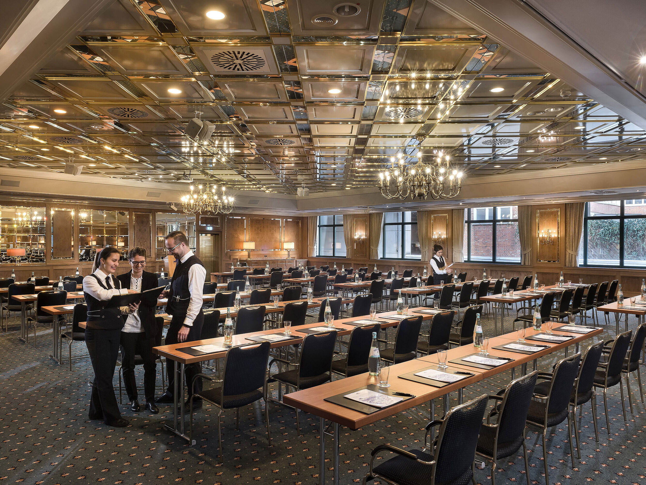 Zwei Mitarbeitende bereiten einen Konferenzraum mit Reihenbestuhlung im Maritim Hotel Stuttgart vor
