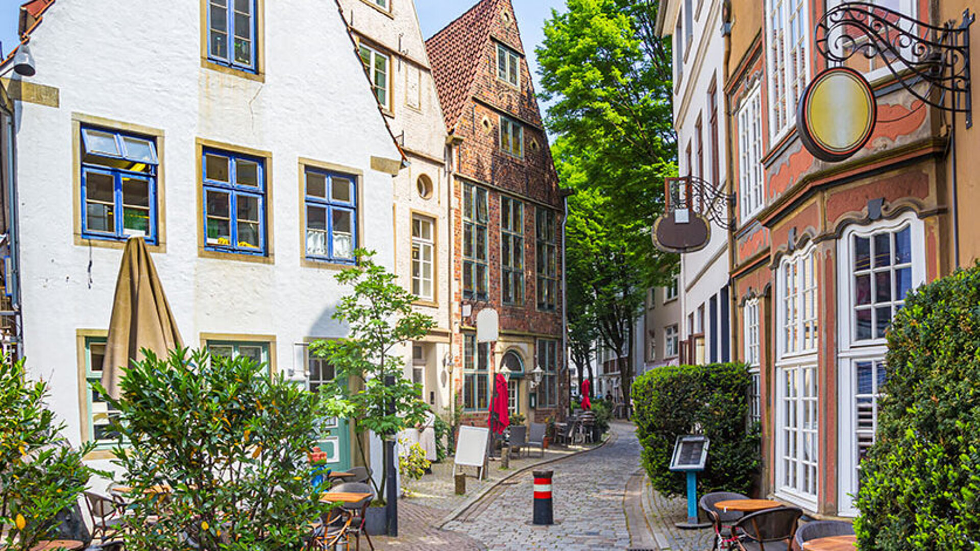 © venemama - AdobeStock.com Historische Gasse im Schnoorviertel in Bremen mit alten Häusern, Kopfsteinpflaster und grüner Bepflanzung