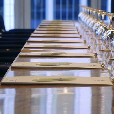 Nahaufnahme eines vorbereiteten Konferenztisches im Maritim proArte Hotel Berlin, mit Notizblöcken und Weingläsern.